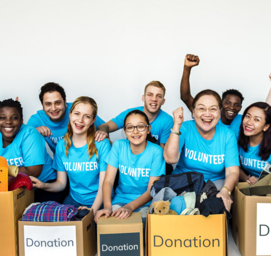 Volunteers posing for a picture in front of donation boxes
