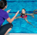 Un entraîneur donne des instructions à ses nageurs artistiques dans la piscine.