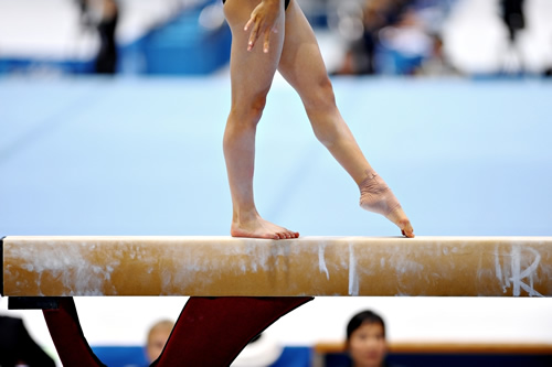 Close up of athlete performing on a balance beam.