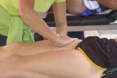 Détail d'un thérapeute en massage traitant le quadriceps d'un athlète.