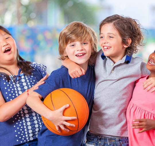 Enfants avec un ballon de basket et leurs bras autour de l'autre