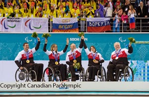 Canadian paralympians celebrating on medal stage.