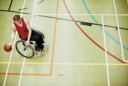 Wheelchair basketball athlete dribbling in a gym.