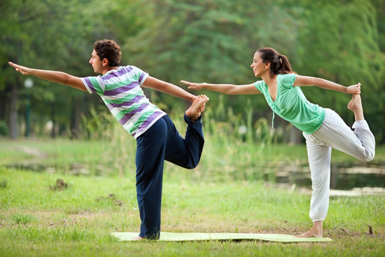 Mother and son performing yoga outside in a field with yoga mats
