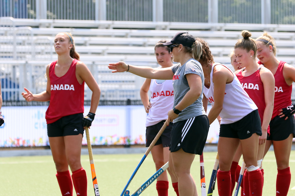 Female field hockey coach going over a drill with the athletes