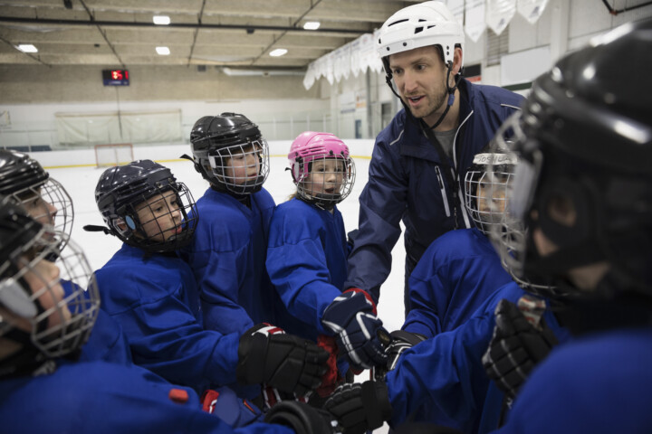 Youth hockey coach in a huddle with his athletes