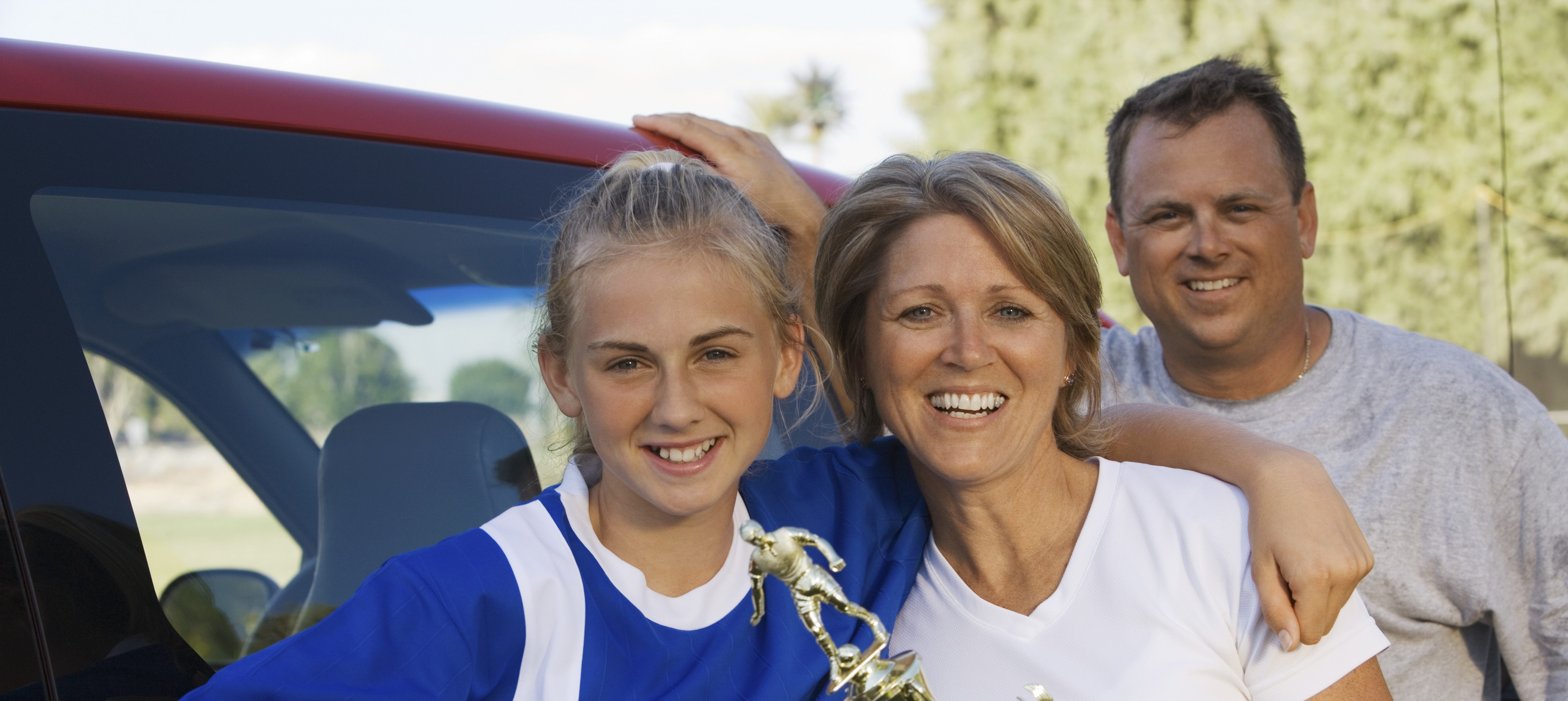 Portrait of happy parents with daughter holding soccer trophy