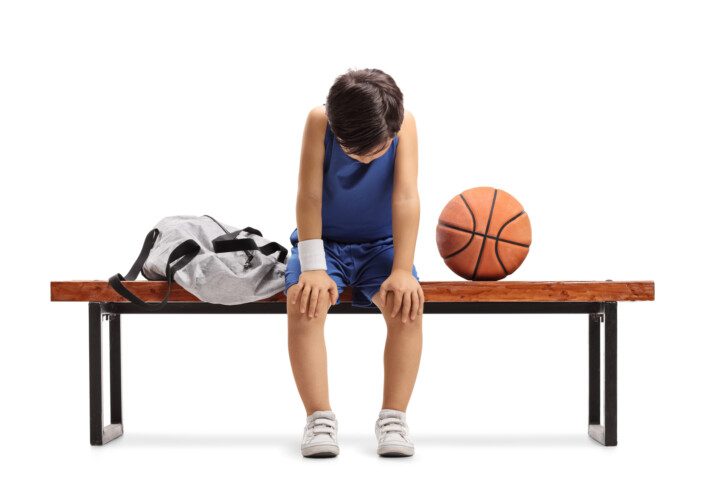 Sad little basketball player sitting on a bench