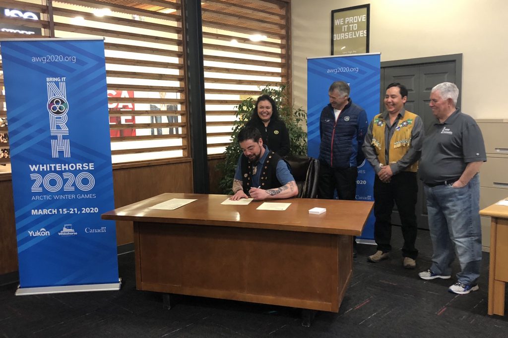 Five people posing next to a Whitehorse 2020 Arctic Winter Games banner