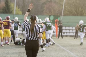 Female football referee giving signals and blurred players in the background
