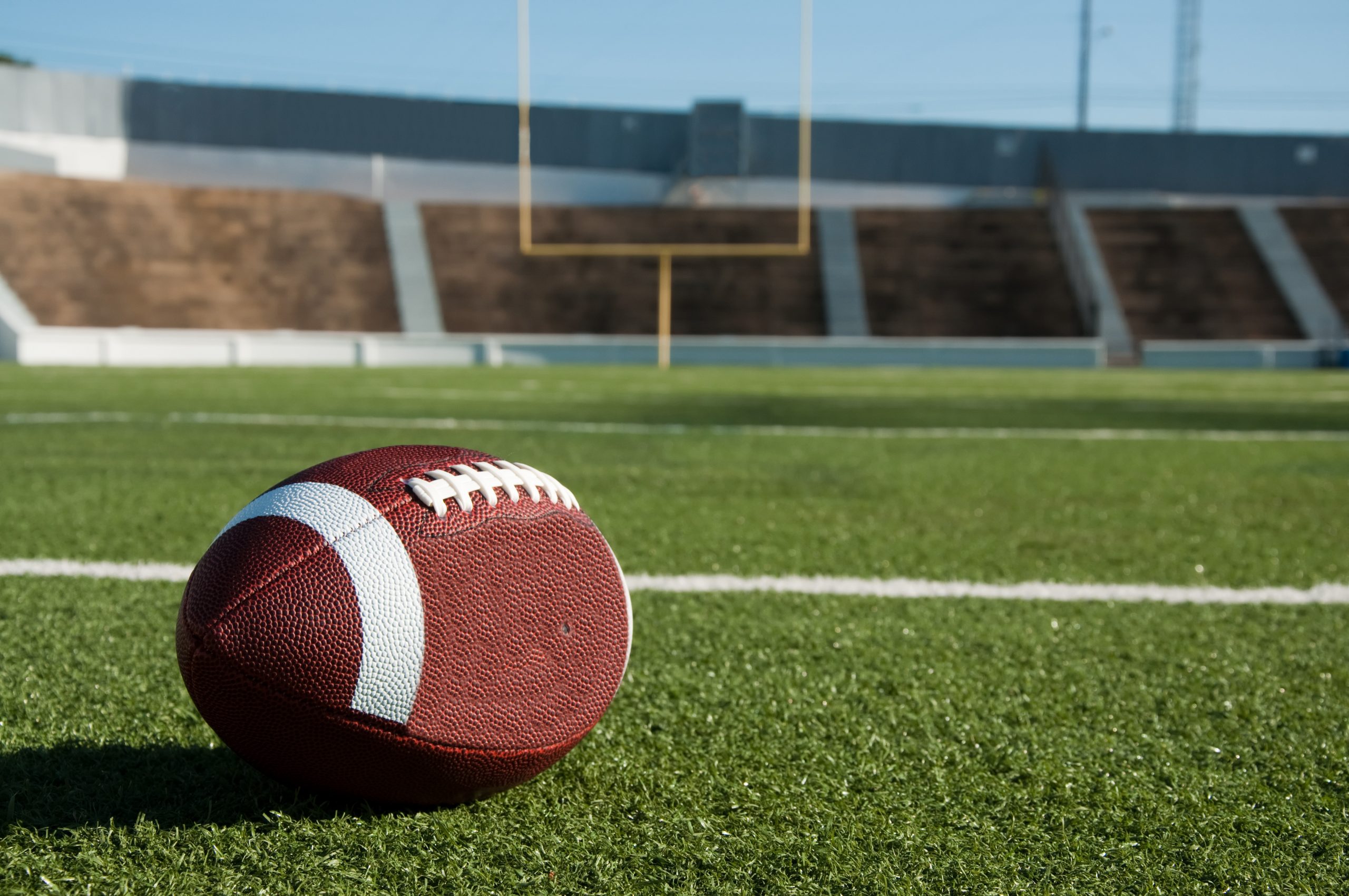 American football on field with goal post in background.