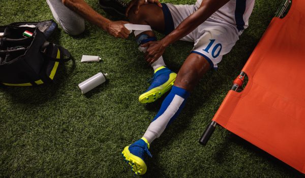 Soccer player injured knee during the game. Sport Doctors provide first aid to player on a professional football field