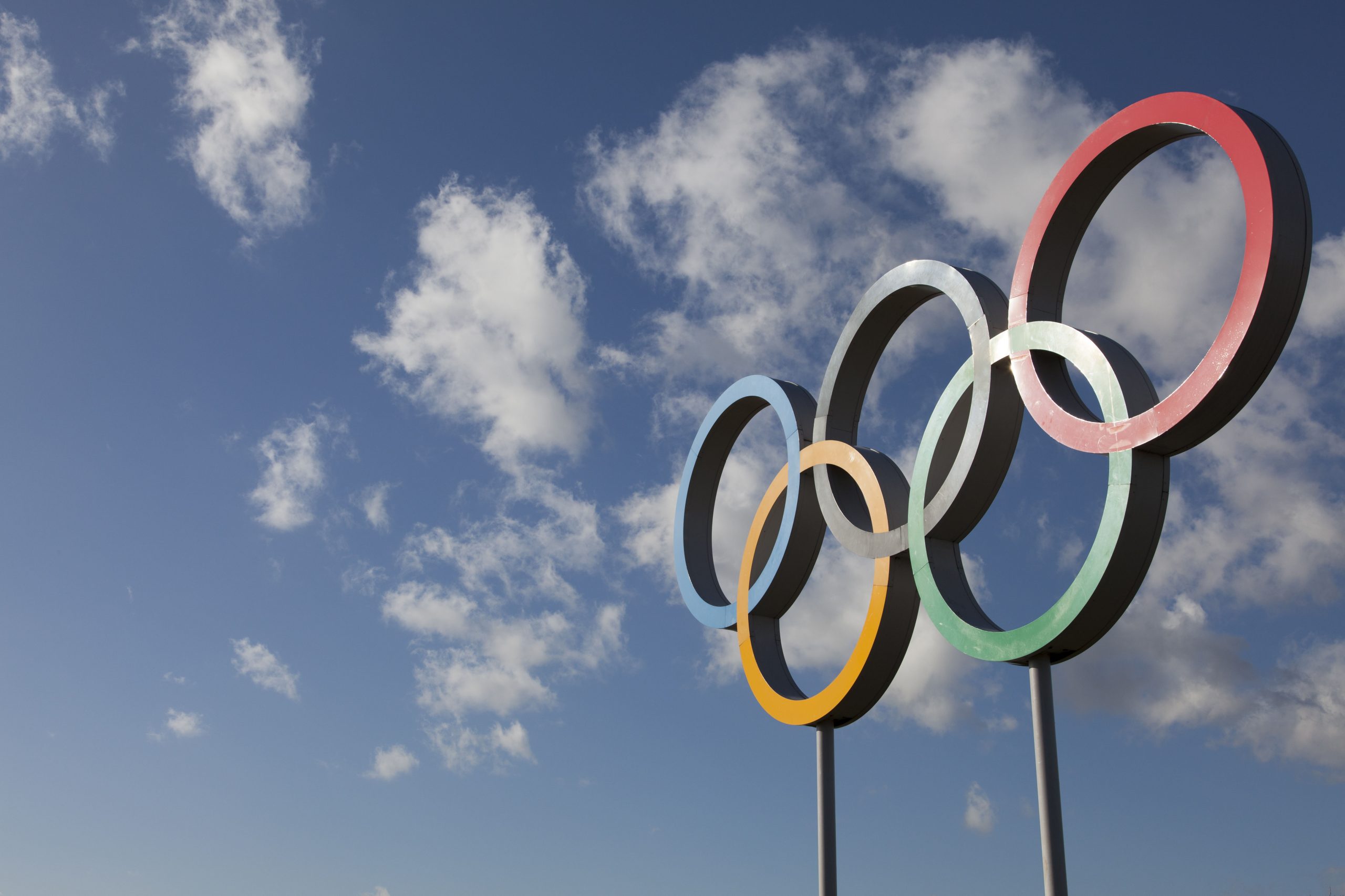 The Olympic symbol, made up of five interconnected coloured rings, under a blue sky.