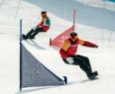 two snowboarders going down the hill during a snowboard cross event