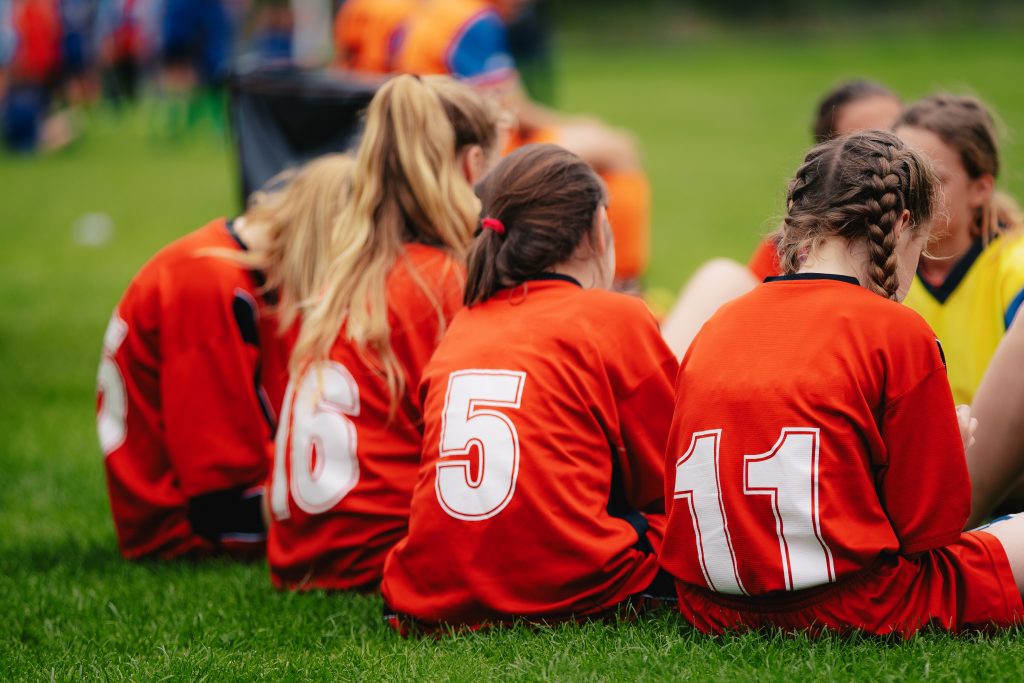 Girls in sports soccer team outdoors. Female physical education class on sports grass field. Young football players of female youth sports team