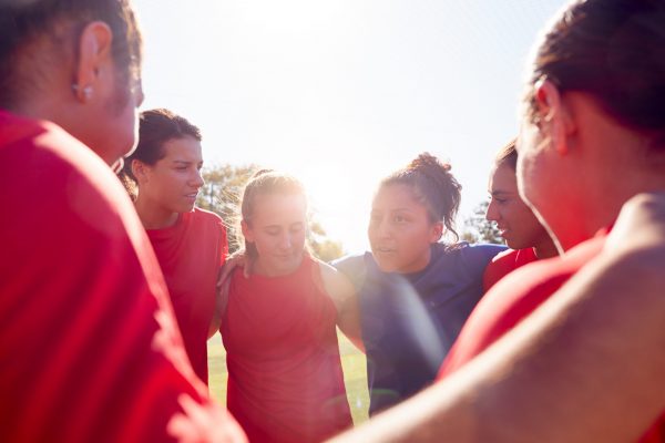 Manager In Huddle With Womens Football Team Giving Motivational Pep Talk Before Soccer Match