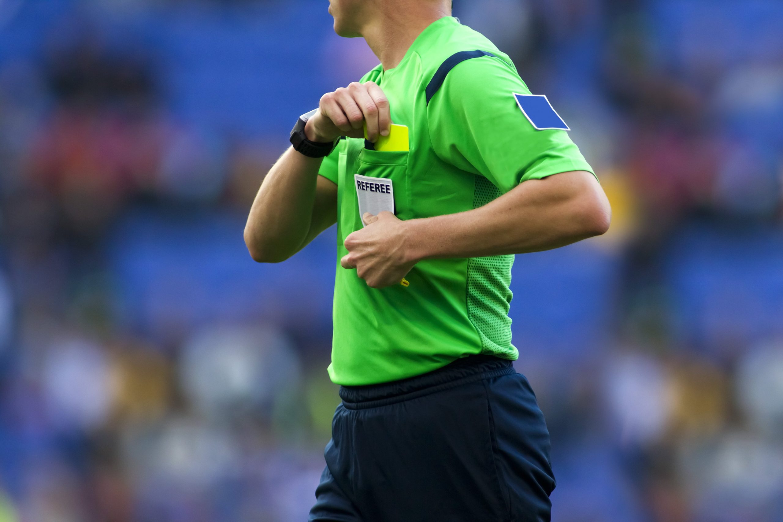 Soccer referee taking yellow card out of pocket.