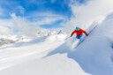 Skier skiing high in mountains in fresh powder snow.