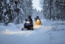 Group of people snowmobiling in forest, winter.