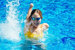 Young female athlete with a disability swimming, happy