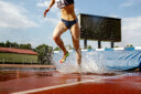 athlète féminine steeplechaser fosse à eau dans la course de steeplechase
