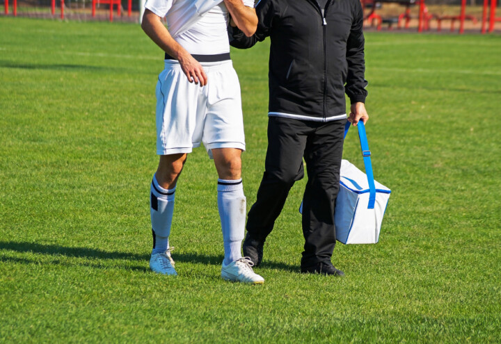 Medic walking with injured soccer player.
