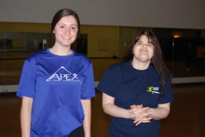 Female APEX participant and trainer standing and smiling together