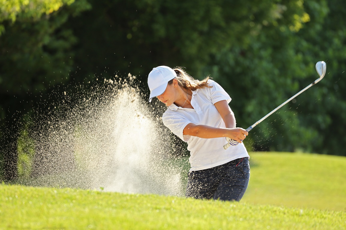 Female golf athlete driving.