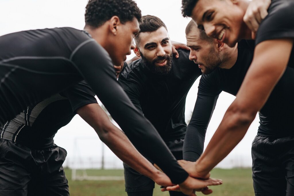 soccer players in a circle with their hands all together in the middle