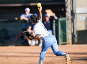 black female varsity athlete throwing a pitch during softball competition