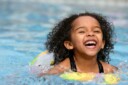 Young girl laughing while swimming.