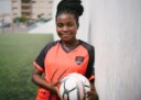 Youth female holding soccer ball in her uniform.