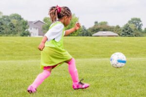 young girl learning to play soccer