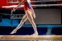 Female gymnast walks on balance beam