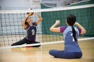 Two young women practice sitting volleyball