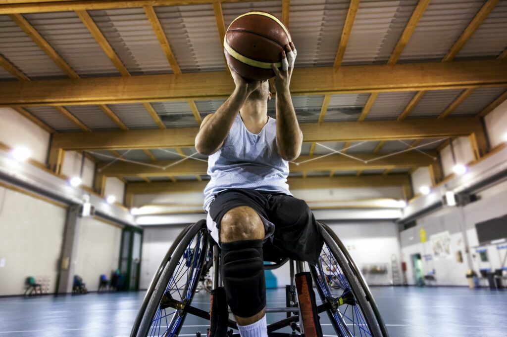 Young adult male getting ready to throw ball during wheelchair basketball game