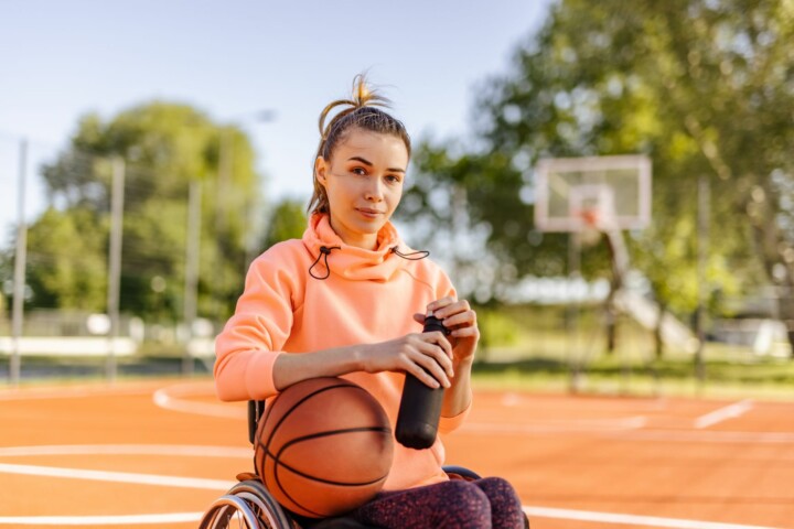 Woman wheelchair basketball player on court.