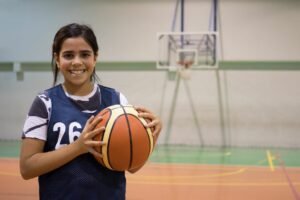 Young diverse girl holding basketball