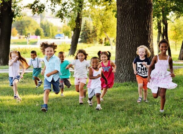 Children joyfully running through a grassy meadow.