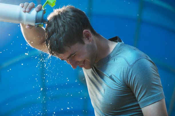 Man pouring water on his head to cool himself down.