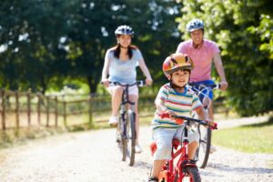 Family biking together down a gravel road during the summer.