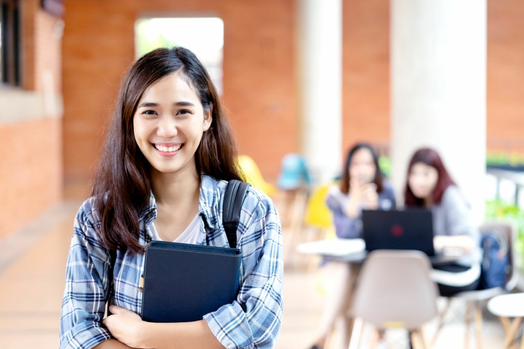 Happy young female student smiling and holding books