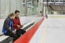 Figure skating coach on the bench showing athlete video on iPad to help improve performance.