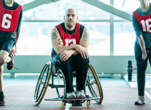 Wheelchair athlete wearing a training jersey on the sidelines of a practice