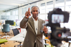 Man wearing headphones speaking into a camera inside an office.