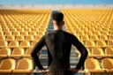 Athlete standing with his back to the camera and looking at many rows of empty seats within an empty stadium.