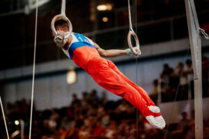 Male gymnast performing on rings.