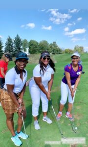 Members of Iron Lady Golf on the golf course, smiling. 