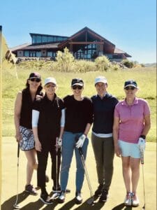 Women standing together and smiling on golf course. Members of Iron Lady Golf. 