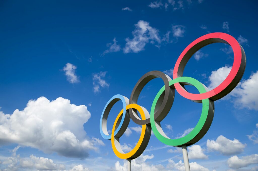 The Olympic symbol, made up of five interconnected coloured rings, under a blue sky